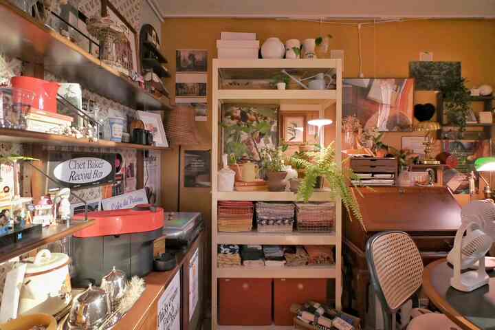 温かみのあるブラウンとナチュラルな色調のダイニングルーム、ラタンチェアや収納棚に植物が配置された雰囲気のあるレトロな空間