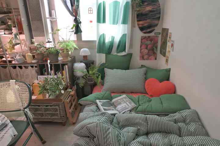 緑色と自然の要素が調和した居心地の良い一人暮らしの寝室、植物とベッドが配置された印象的な空間