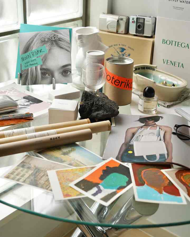 透明なガラステーブルにポスターや様々なオブジェが配置された玄関のインテリア