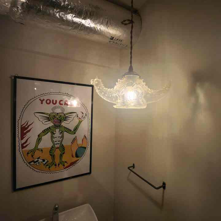 白を基調としたバスルーム、怪獣形のソフビ照明と額入りポスターが配置された印象的な空間