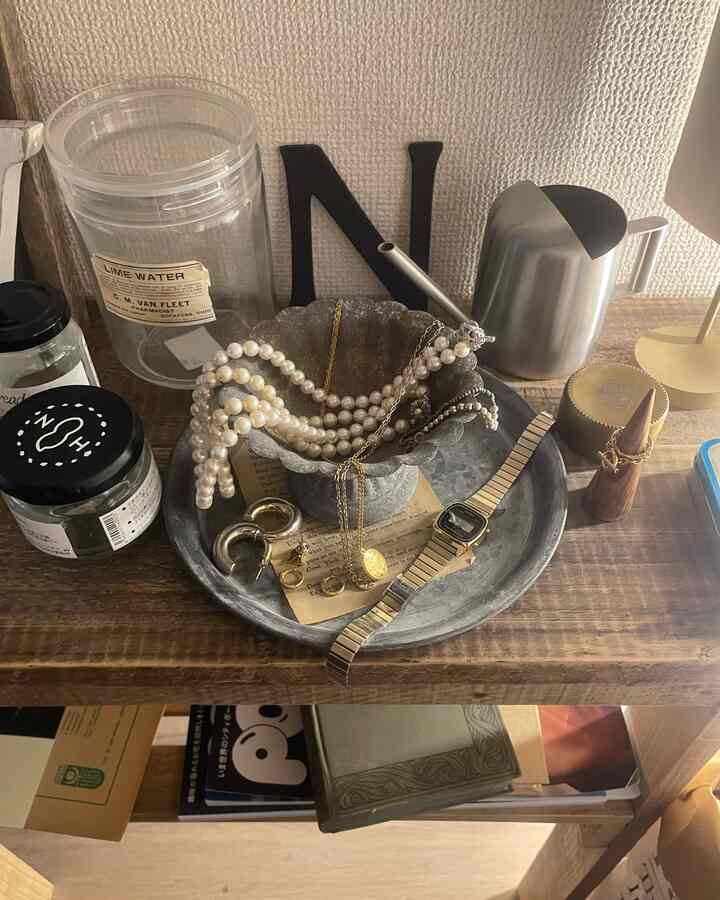 ゴールドのアクセサリーが乗ったメタルトレイと木製の棚が調和する温かみのある空間