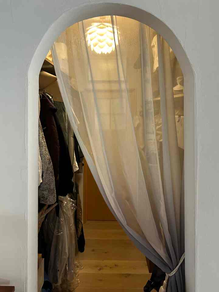 白と木目調の色調のある4人暮らし向けアーチ型入口のあるファミリークローゼット、実用的な収納アイデアが配置された空間