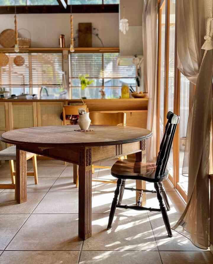 温かみのある木目調と自然光が印象的なダイニング、円卓と椅子が配置された雰囲気のあるナチュラルな空間