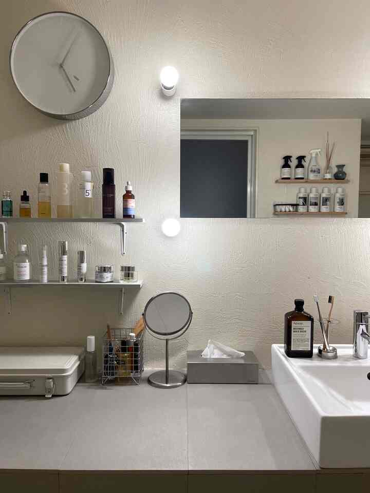 白とシルバーの色調のパウダールーム、整然と並べられたスキンケア製品と鏡が配置された清潔感のあるインテリア