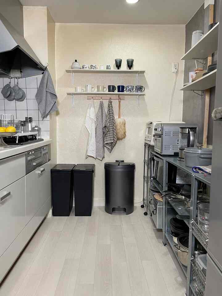 白とグレーの色調の狭いキッチン、オープンシェルフと実用的な収納アイデアが調和した清潔感あるインテリア