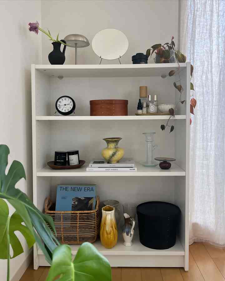 白い棚に複数の花瓶や小物が整然と配置された、自然を感じるリビングの雰囲気のあるインテリア