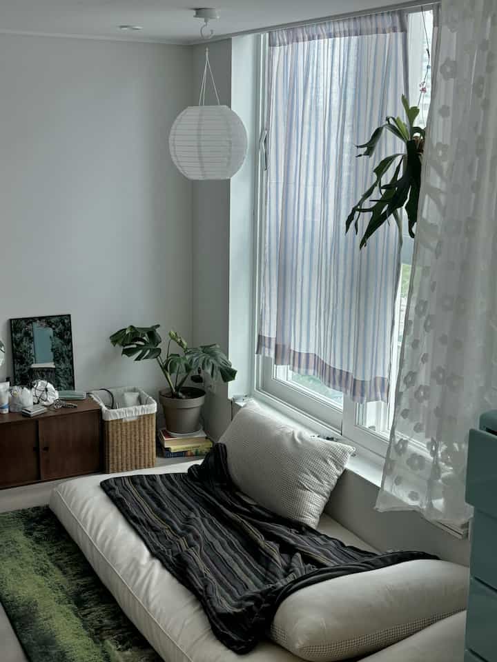 白と緑の色調のウォークインクローゼット、窓際にスローとカーテンがある落ち着いた雰囲気の空間