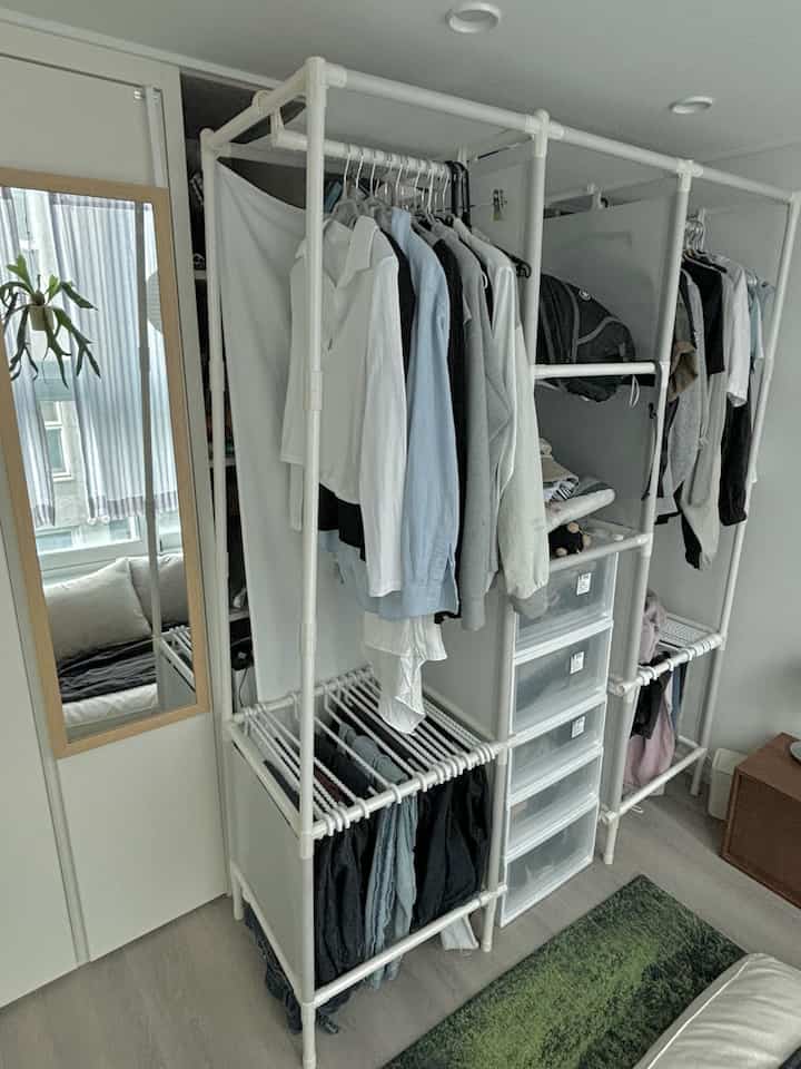 白を基調としたウォークインクローゼット、中央にモジュール型のハンガーと収納ボックスが整然と配置された実用的な収納空間