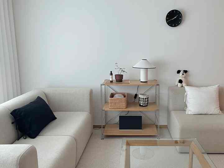 アイボリーと木目調が調和したシンプルでモダンなリビング、黒いアクセントと整った棚が配置された落ち着いた空間