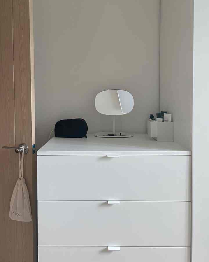 白いドレッサーの上に卓上鏡と小物が置かれたシンプルな空間