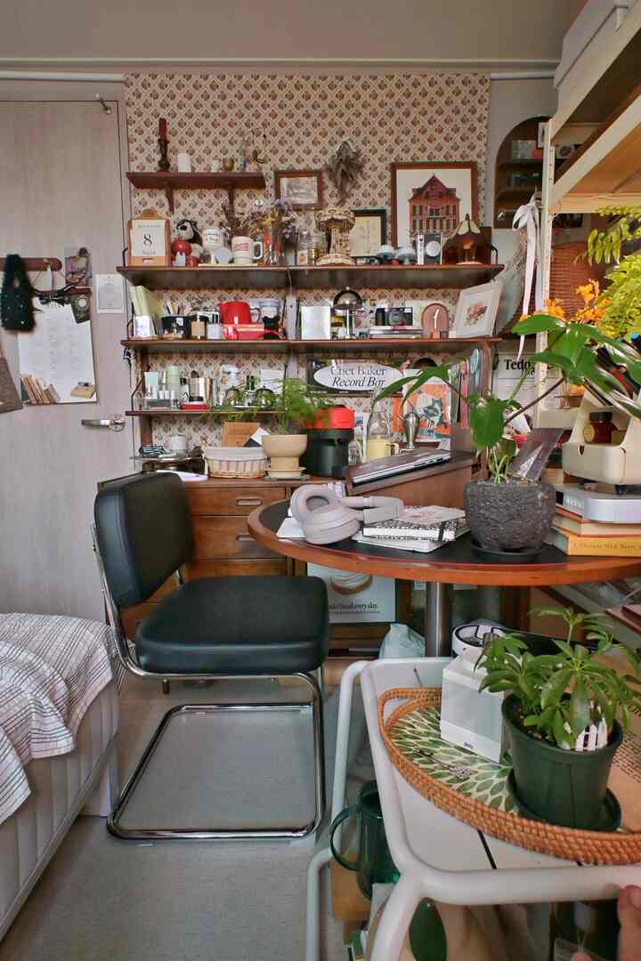 ヴィンテージの花柄カーテンと濃い木目調の棚がある4.5畳のワンルーム作業空間、多彩な植物と小物で雰囲気のあるインテリア