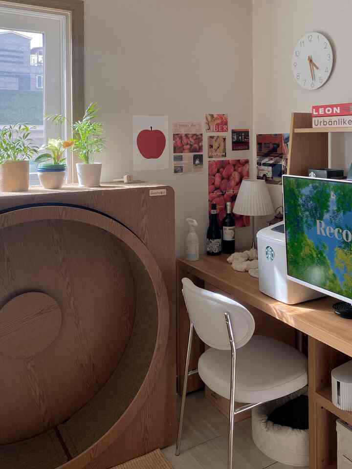 木目調と白を基調としたホームオフィス空間、キャットタワーと植物が配置された清潔感のある小さな部屋