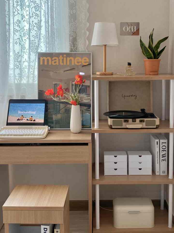 明るいウッドトーンとホワイトの小さなウォークインクローゼット、中央に化粧台とノートパソコン、棚の上にターンテーブルと植物が配置された印象的なインテリア