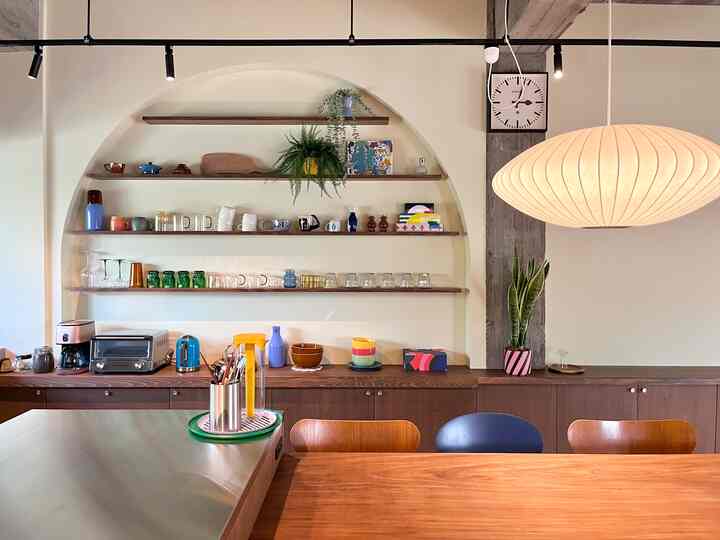 ブラウンとホワイトの色調のキッチン空間、コーヒーメーカーとダイニングチェアが配置された暖かくモダンなインテリア