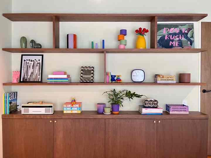 ブラウンのナチュラルトーンの壁面キャビネットと棚に多様なオブジェや本が配置された印象的で温かみのある空間