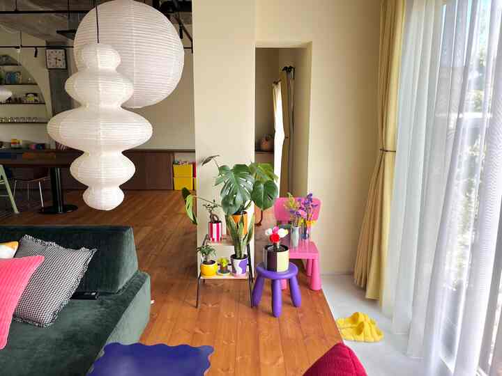 ナチュラルな木目調と大型窓のリビング、子供用家具と植物が配置された明るく居心地の良い空間