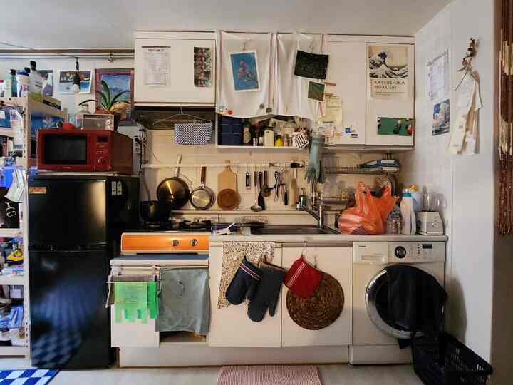 白を基調とした狭いキッチン、実用的な収納アイデアと多様な調理器具が配置された雰囲気のあるインテリア