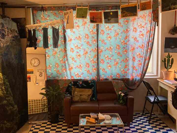 ブラウンのレザーソファと花柄の青いカーテンが配置されたレトロなリビングルーム
