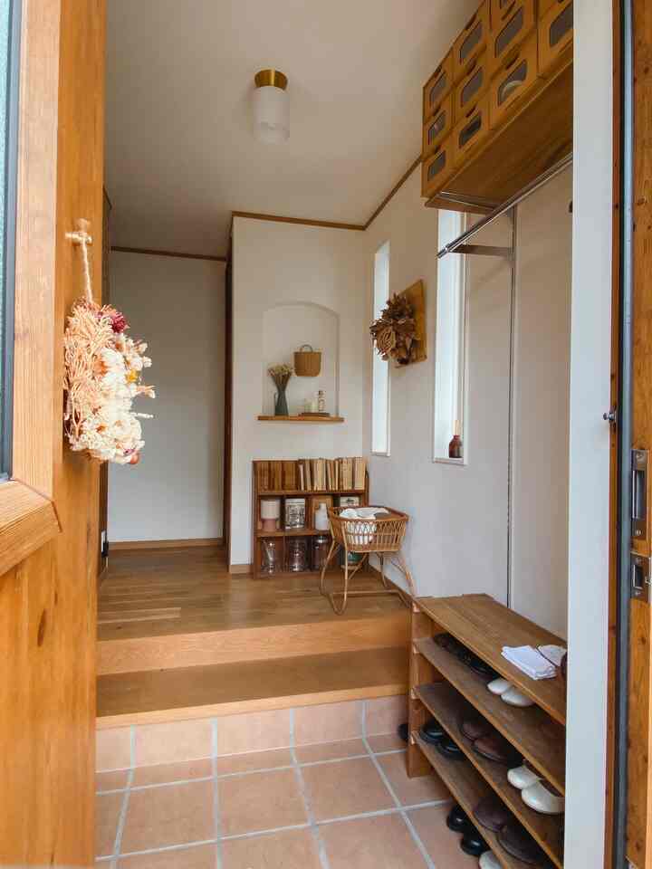 白い壁と木目調の家具が配置された狭い玄関、整った収納と自然な雰囲気のあるインテリア