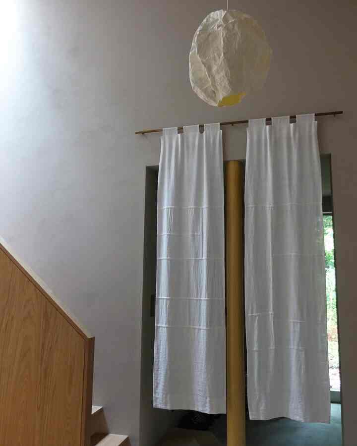 白と木目調の玄関、和紙の照明とリネンの暖簾が配置された自然で和モダンな印象的な空間