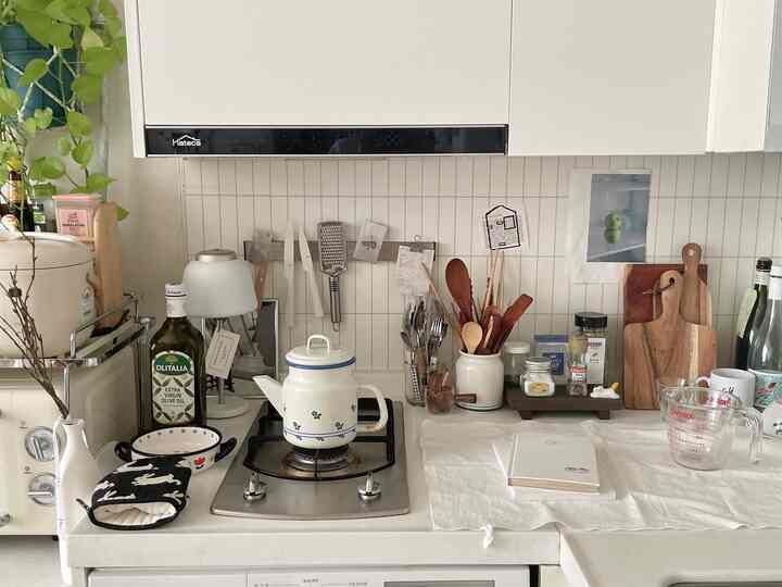 アイボリーと木目調が調和したキッチン、さまざまな調理器具とまな板が温かみのある雰囲気を演出するインテリア