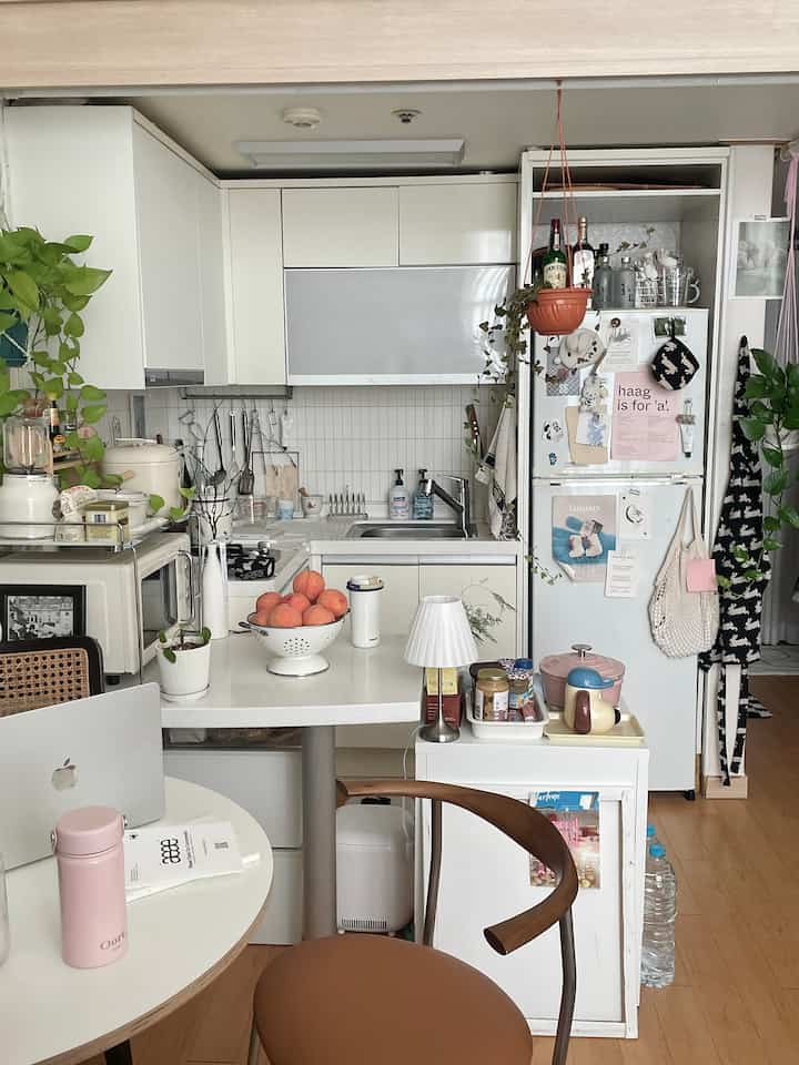 ホワイトとブラウンのトーンが基調のコンパクトなキッチン、ダイニングテーブルと椅子が配置された印象的な空間