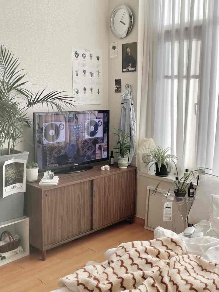 ナチュラルな色調のリビング、木製のテレビ台と植物が配置された明るく落ち着いたインテリア