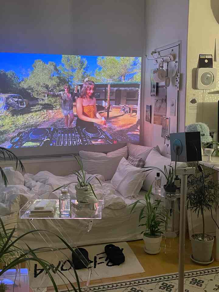 ホワイトとナチュラルトーンのリビング、大きなホワイトソファと透明アクリルテーブルが配置された雰囲気のあるホームシネマ空間