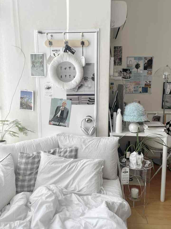 ホワイトとナチュラルトーンの寝室、ベッドとチェック柄クッション、壁のデコレーションが調和した居心地の良いインテリア