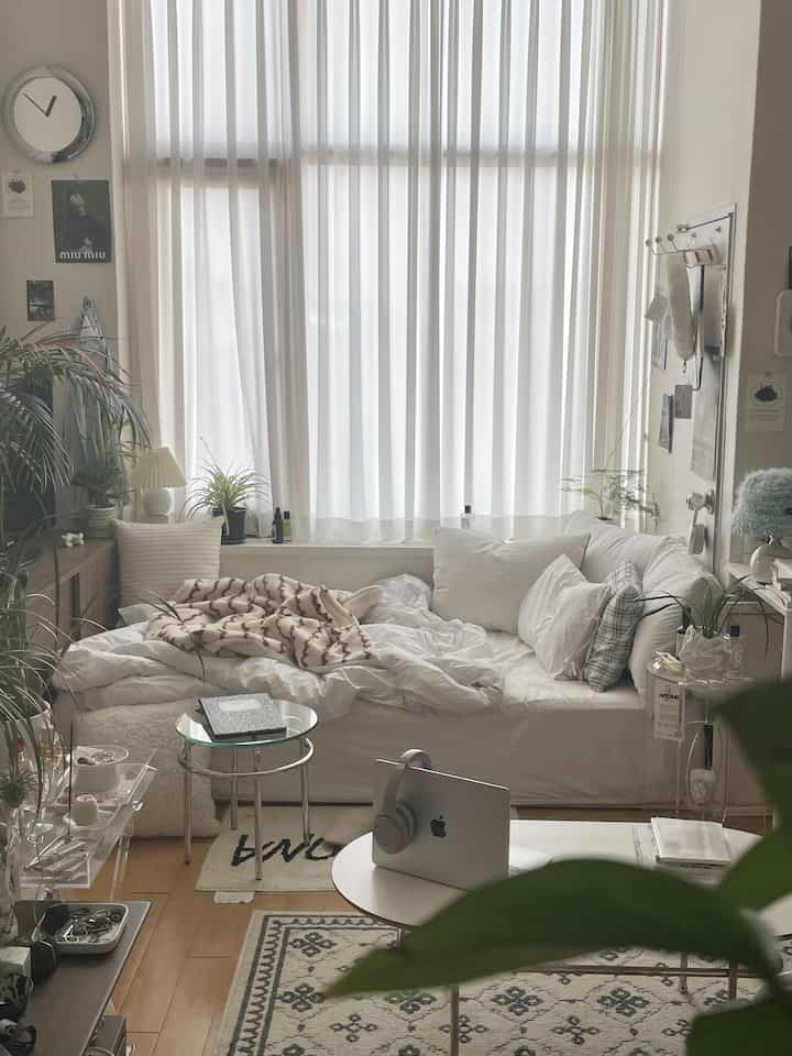 白とベージュの色調の寝室、カーテンとソファベッドが配置された自然の雰囲気のある空間