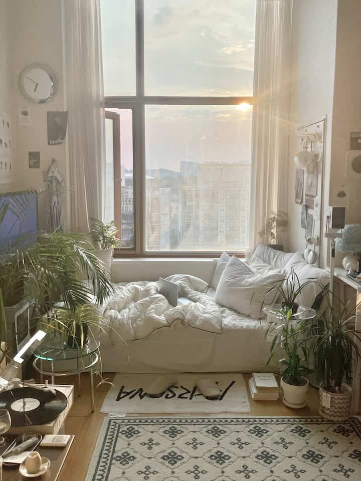 白とベージュ調の小さなリビング、アナログオーディオ機器と植物が配された自然で落ち着いた雰囲気のインテリア