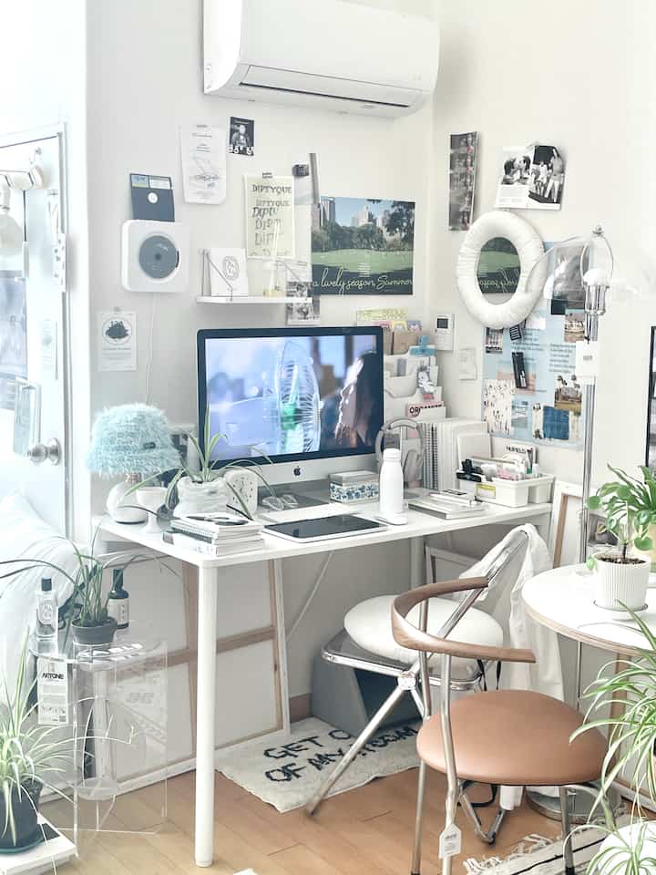 白と木目調が調和した一人用デスクゾーン、壁の装飾と多機能椅子が配置された落ち着いた作業空間