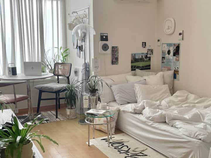 ホワイトとベージュの色調が特徴の一人暮らし用寝室兼リビング、ナチュラルスタイルでホームオフィスを備えた居心地の良いインテリア