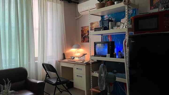 明るいベージュとブラックのトーンの小さなホームオフィス、机と折りたたみ椅子が配置された落ち着いた雰囲気の空間