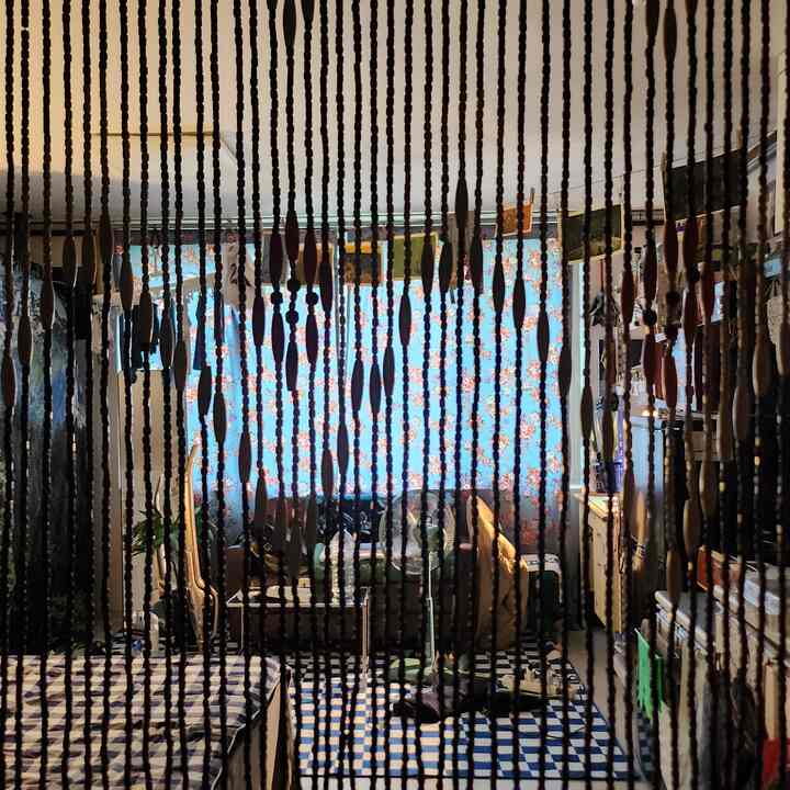 ウッドトーンとブルーの色調の狭いリビング、木製ビーズののれんが空間を仕切るレトロな雰囲気のインテリア