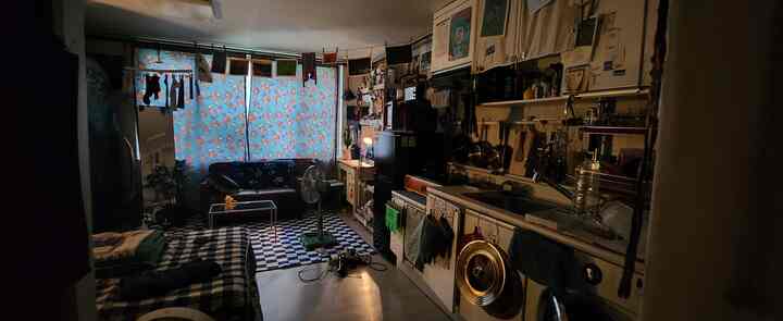 青い花柄カーテンとヴィンテージスタイルのソファがある、狭くコンパクトなリビングとキッチンの雰囲気のあるインテリア