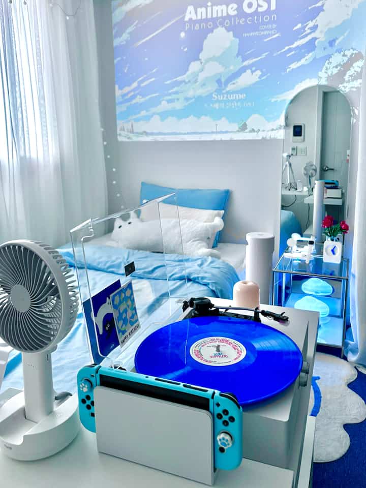青と白のトーンの寝室、ベッドとブルーのレコード、アニメOSTのプロジェクションが壁に映し出された雰囲気のあるインテリア