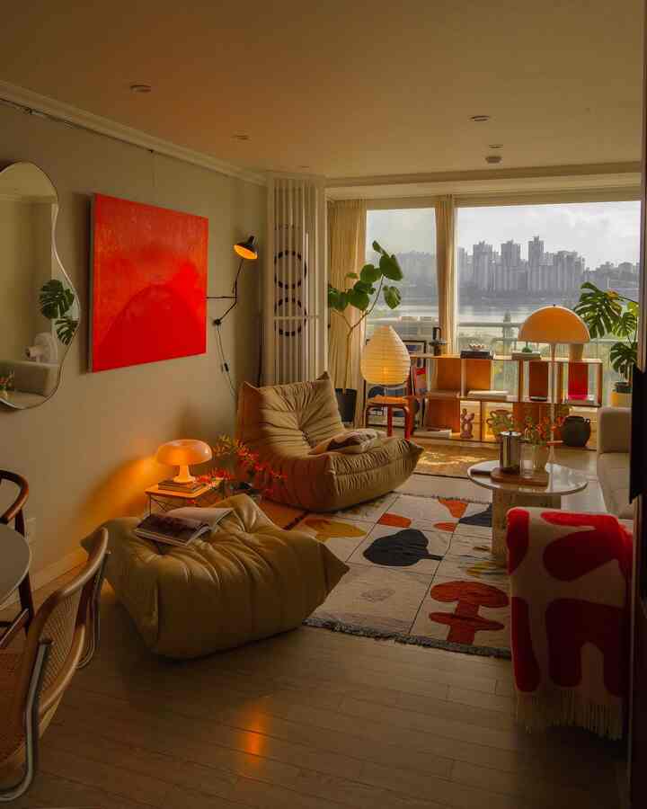 ベージュと赤のトーンが調和するリビング、快適なソファと抽象画が配置されたナチュラルモダンなインテリア