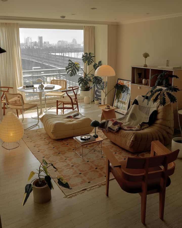 ベージュとブラウンのトーンのリビング、快適なソファとアームチェア、円形のダイニングテーブルが配置されたナチュラルモダンなインテリア