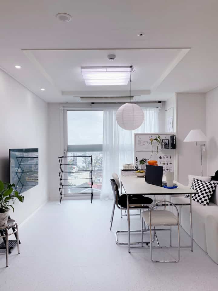 ホワイトとブラックの色調が調和したワンルームのダイニング、モダンなソファとダイニングテーブルが配置された印象的な空間