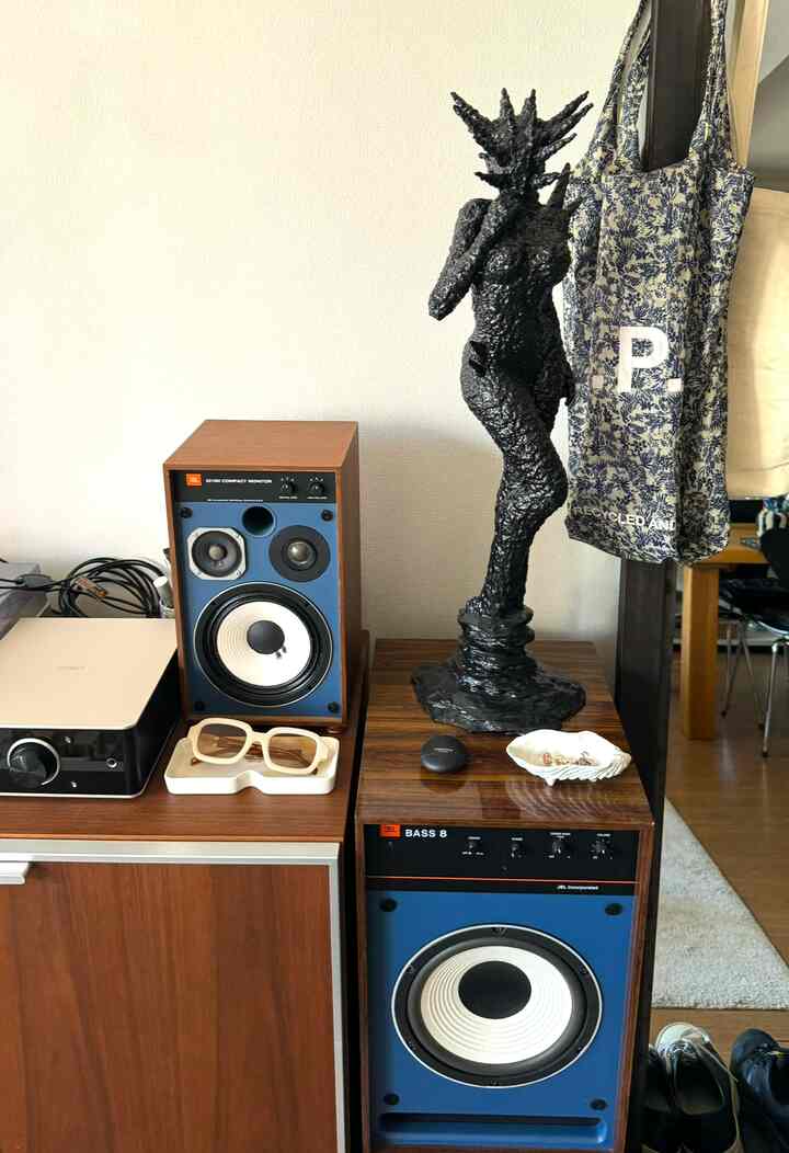 ブラウンの木目調と青を基調にした空間、中央に独特な黒いオブジェがあり、トレイに眼鏡が置かれたインテリア