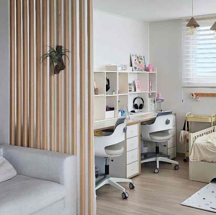 ホワイトとウッドトーンの子供部屋、二つの子供用机とソファが配置された雰囲気のある空間