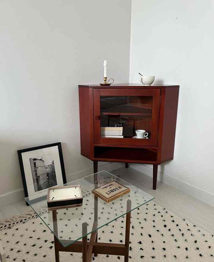 ブラウン調のコーナーガラスキャビネットが配置されたミニマルでナチュラルモダンな空間