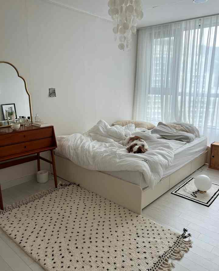 ホワイトとウッドトーンの調和が美しい寝室、快適なベッドと窓辺のカーテンが配置された自然派モダンなインテリア