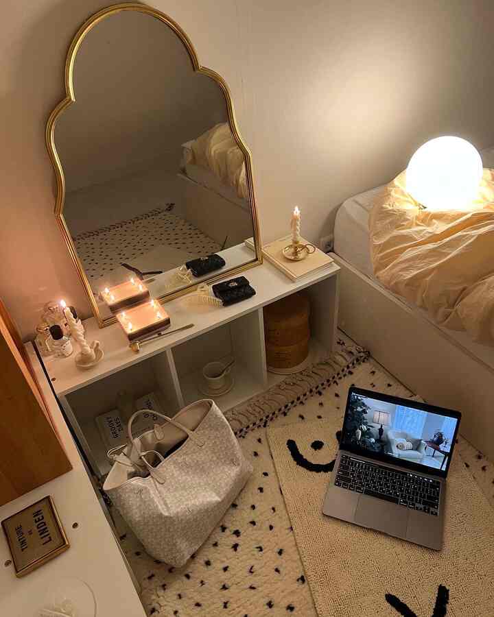 ホワイトとゴールドのトーンの寝室、居心地の良いキャンドルと黄色の寝具が配置されたコンパクトな空間