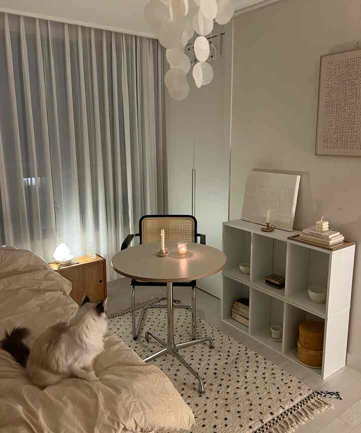 ベージュとホワイトの色調のリビング、ベージュのソファとテーブル、キャンドル、くつろぐ猫が配置された雰囲気のある空間