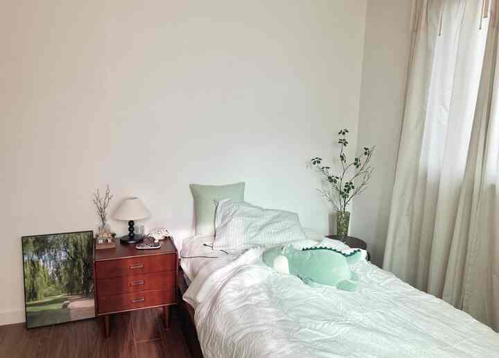 白と茶色の色調の寝室、中央にベッドとナイトテーブルが配置された自然で落ち着いた雰囲気のある空間