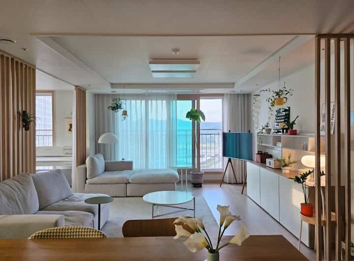 ホワイトとウッドトーンが調和した4人暮らしのリビング、広く開放感のあるモダンミニマルなインテリア