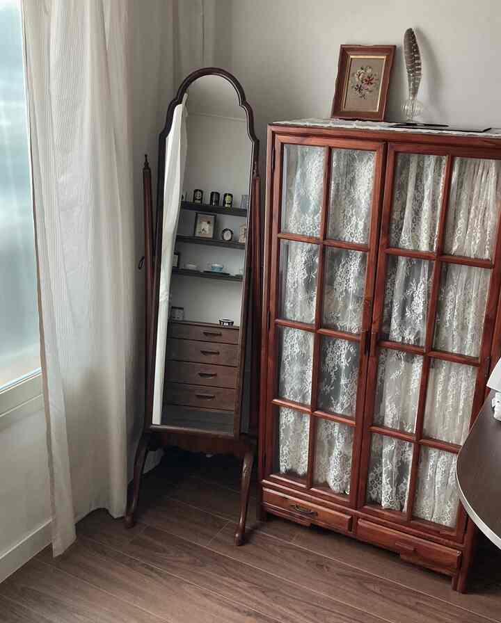 木目調のヴィンテージミラーとキャビネットが置かれた落ち着いたリビングのコーナー