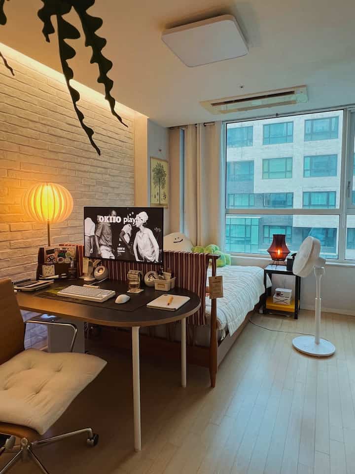 ナチュラルカラーの寝室兼ホームオフィス、ベッドフレームとデスクが配置された雰囲気のある空間